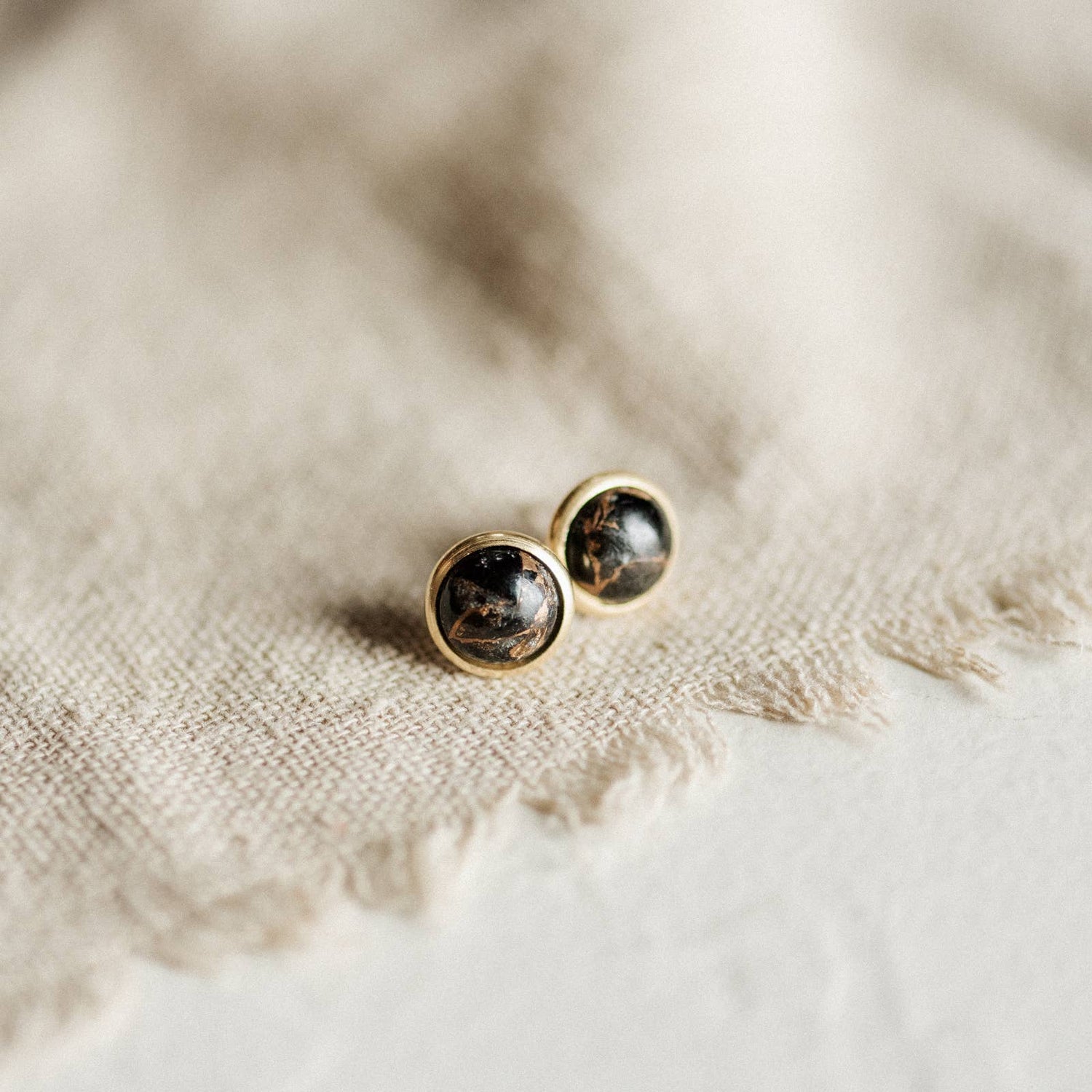 A pair of gold earrings with black/gold stones