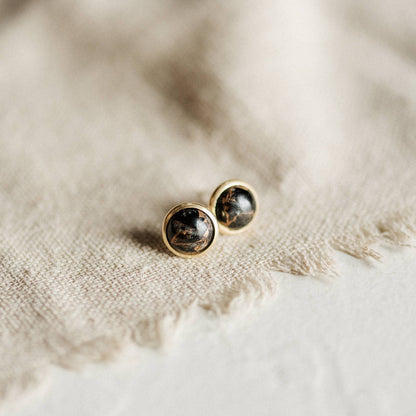 A pair of gold earrings with black/gold stones